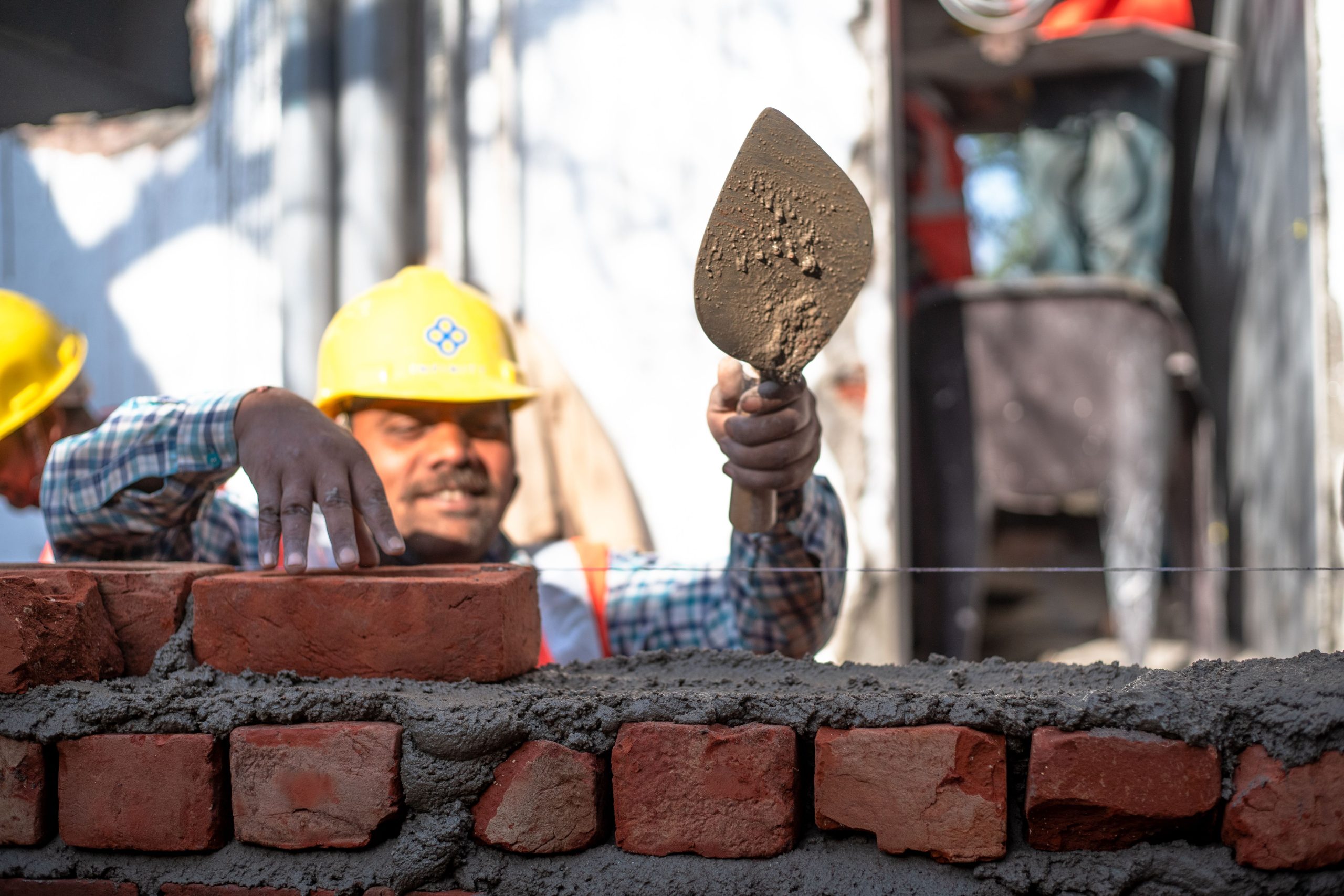 Two construction workers building a brick wall at a site in Delhi, India.